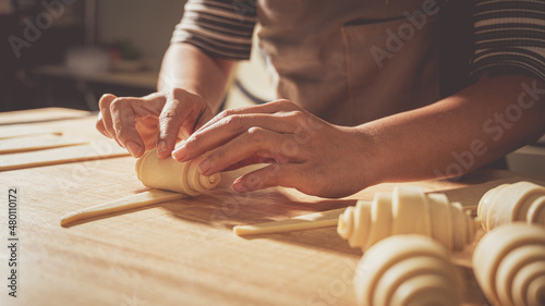Fényképezés Young pastry chef making some croissant in the bakery