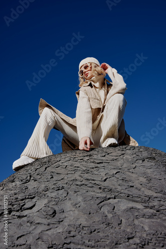 young woman sitting on a stone nature blue sky in a hat lifestyle