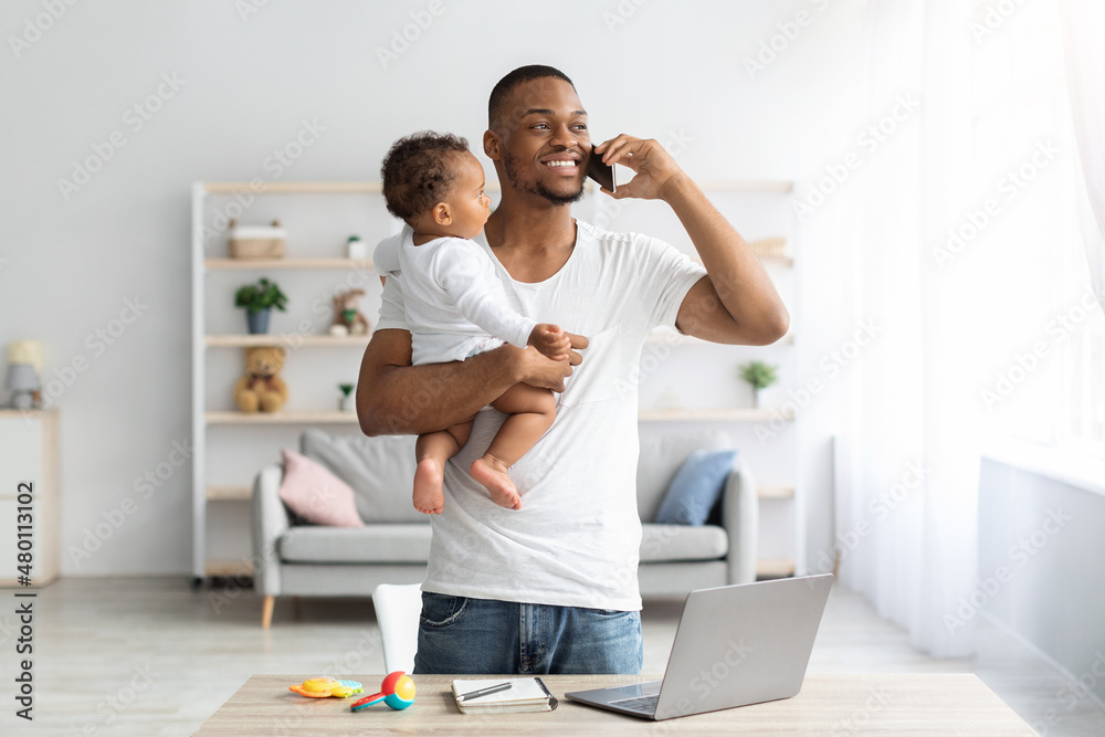 Black Man With Baby Talking On Cellphone While Working At Home Office Black Man With Baby Talking On Cellphone While Working At Home Office