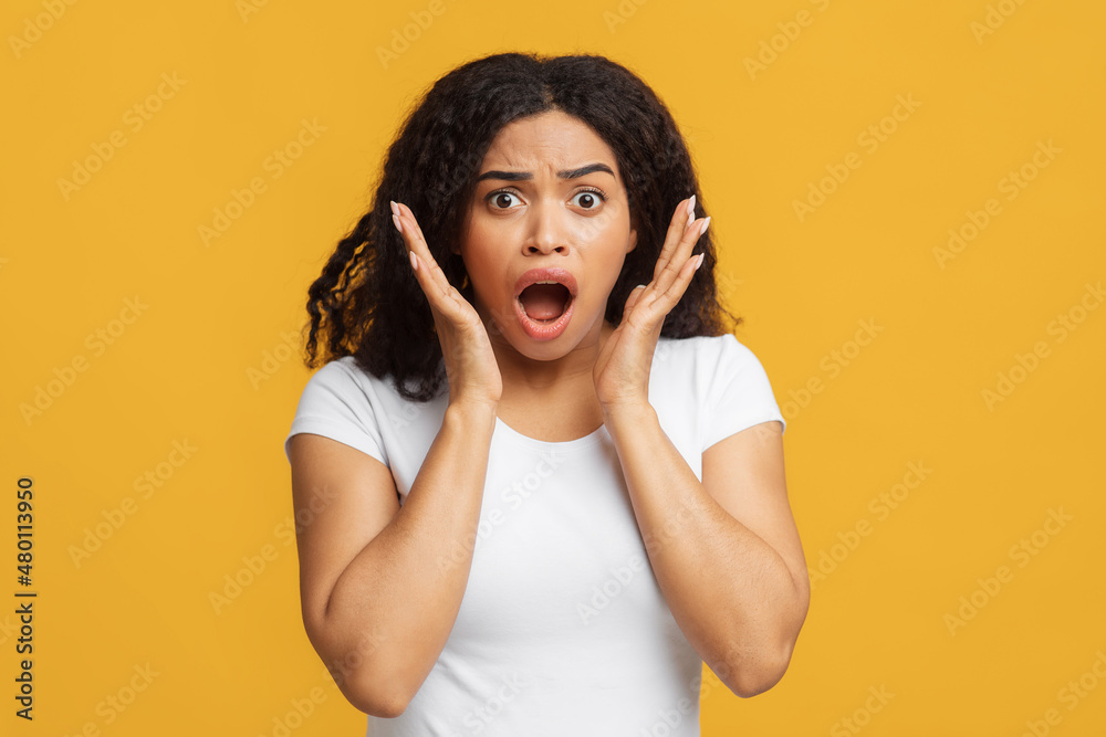 Fototapeta premium Oh no. Shocked african american woman looking at camera and emotionally reacting to news or offer, yellow background