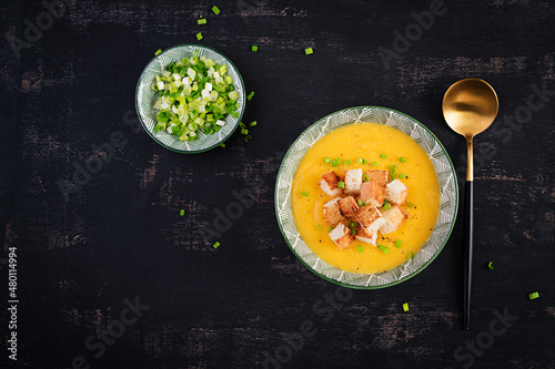 Creamy pumpkin puree soup with croutons, peppers and green onions. Top view, above