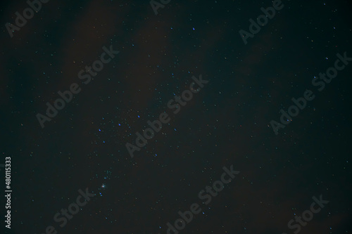 Blurry night sky and Orion Constellation. Black wallpaper with universe concept. M42 nebula visible in the evening. No selective focus, defocused background.