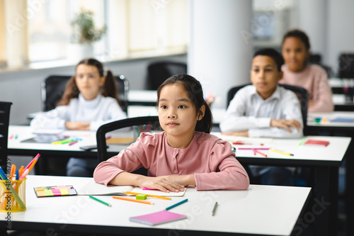 Portrait of focused asian girl sitting at desk in classroom