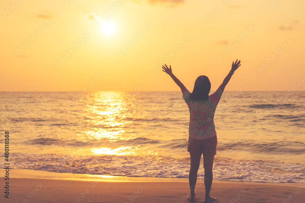 Fototapeta premium Copy space of woman rise hand up on sunset sky at beach and island background.