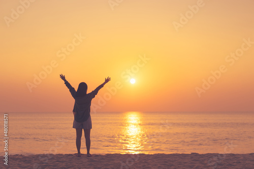 Copy space of woman rise hand up on sunset sky at beach and island background.