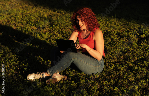 Business woman in red clothes works with laptop ooutdoors. photo