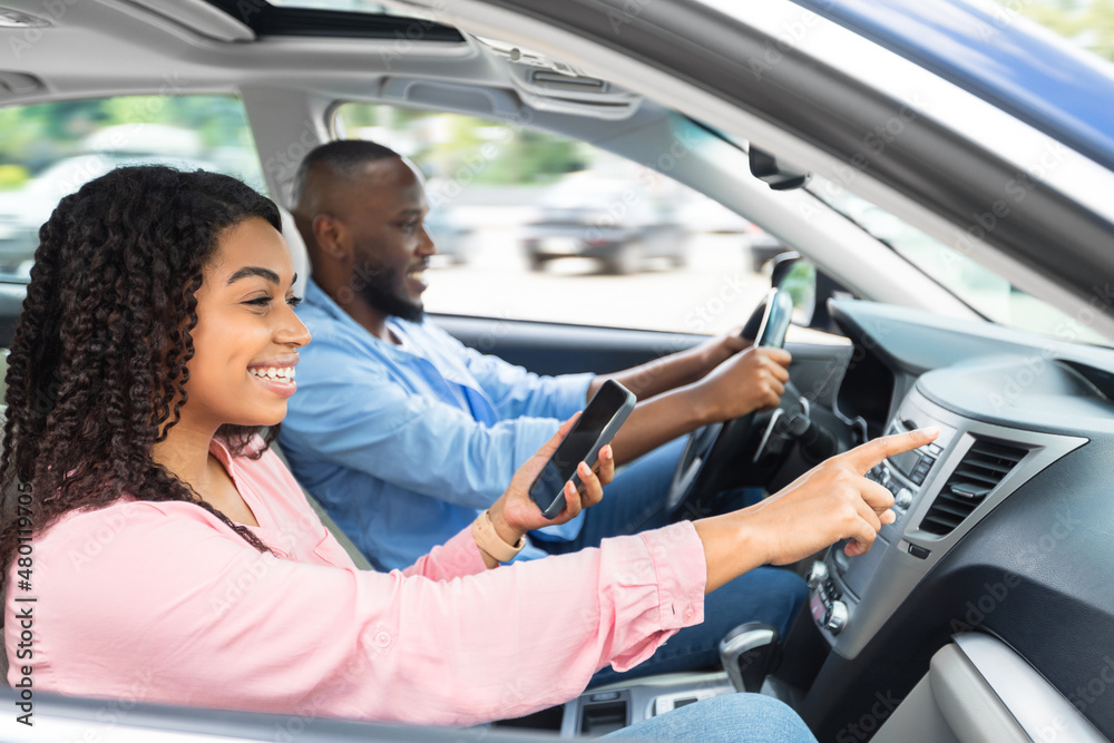 Happy black couple driving car and using cell phone Happy black couple driving car and using cell phone