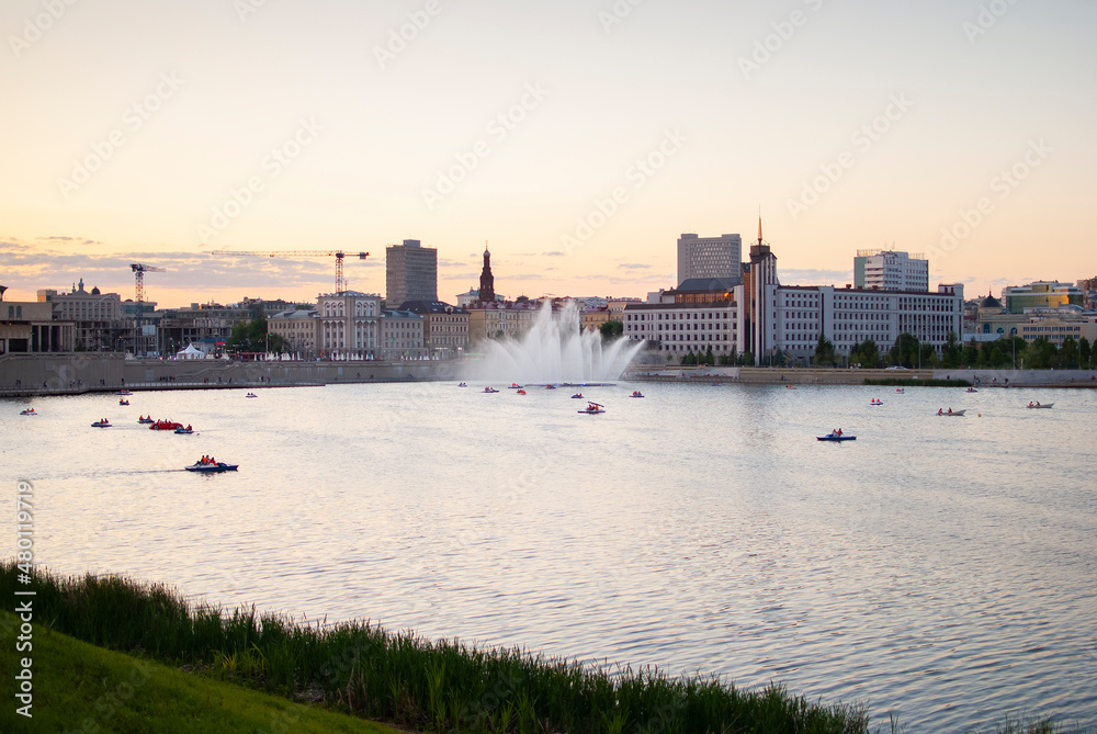 Obraz premium boats with people floating on the river against the background of city buildings at sunset