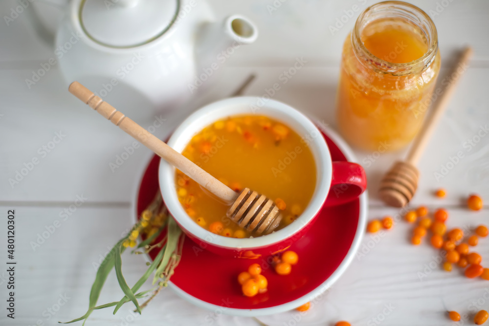 Herbal hot tea with buckthorn and honey on white wooden background. Hot drinks with vitamins Herbal hot tea with buckthorn and honey on white wooden background. Hot drinks with vitamins