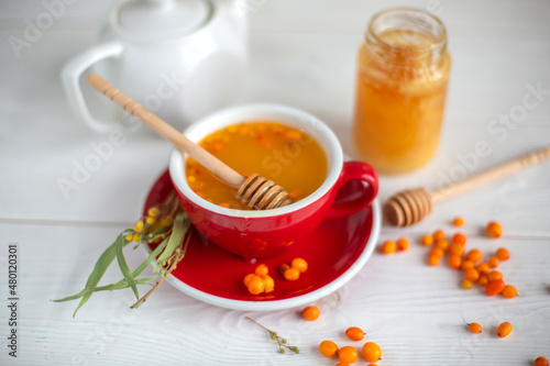 Herbal hot tea with buckthorn and honey on white wooden background. Hot drinks with vitamins