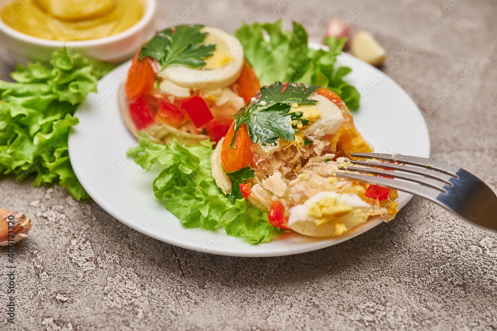 Portion of delicious chicken aspic on a plate isolated on concrete table Portion of delicious chicken aspic on a plate isolated on concrete table