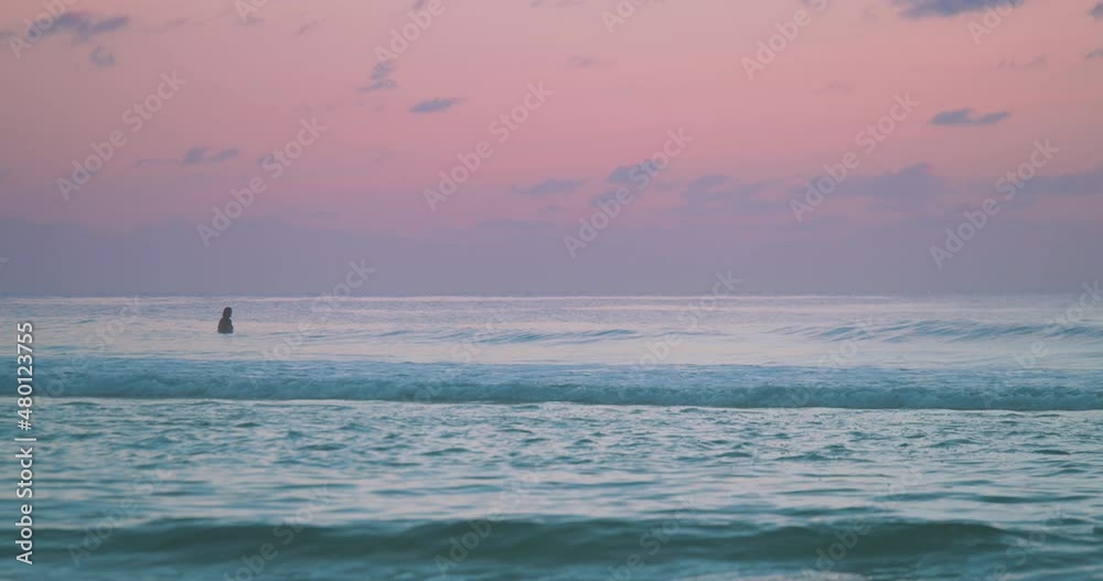 A striking pink and blue ocean sunset with one single person in the water. Slow motion. A striking pink and blue ocean sunset with one single person in the water. Slow motion.