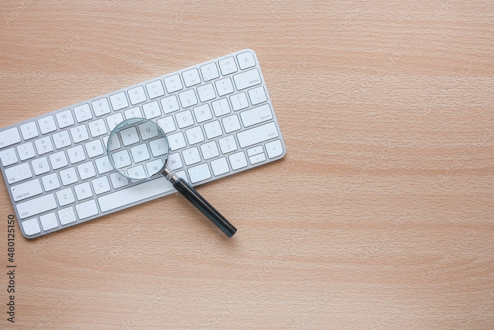 A magnifying glass on the computer keyboard A magnifying glass on the computer keyboard