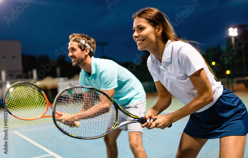 Beautiful young people are playing tennis as a team on tennis court outdoors. People sport concept © NDABCREATIVITY