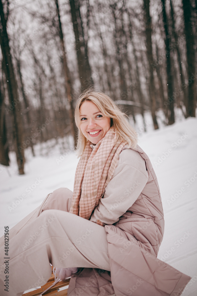 a beautiful young girl rides a sleigh in the winter forest, winter entertainment, a girl runs with a sleigh in the park a beautiful young girl rides a sleigh in the winter forest, winter entertainment, a girl runs with a sleigh in the park