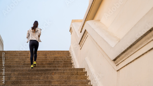 Confidence Hispanic woman in sportswear running up stairs on the bridge in city. Healthy wellness female athlete enjoy outdoor lifestyle sport training workout exercise fitness jogging in summer
