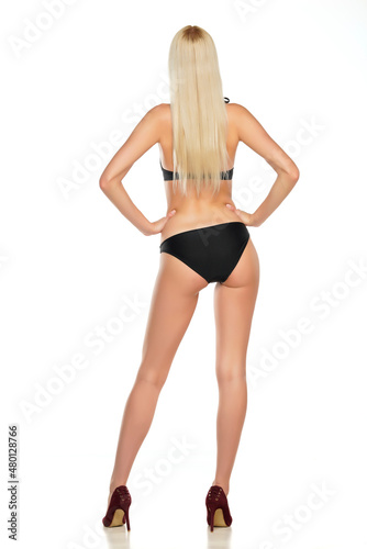 Rear view of a young blond woman posing in swimsuit on a white