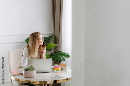 Foto Young  business woman smile and talk on phone while she looking trough the windo