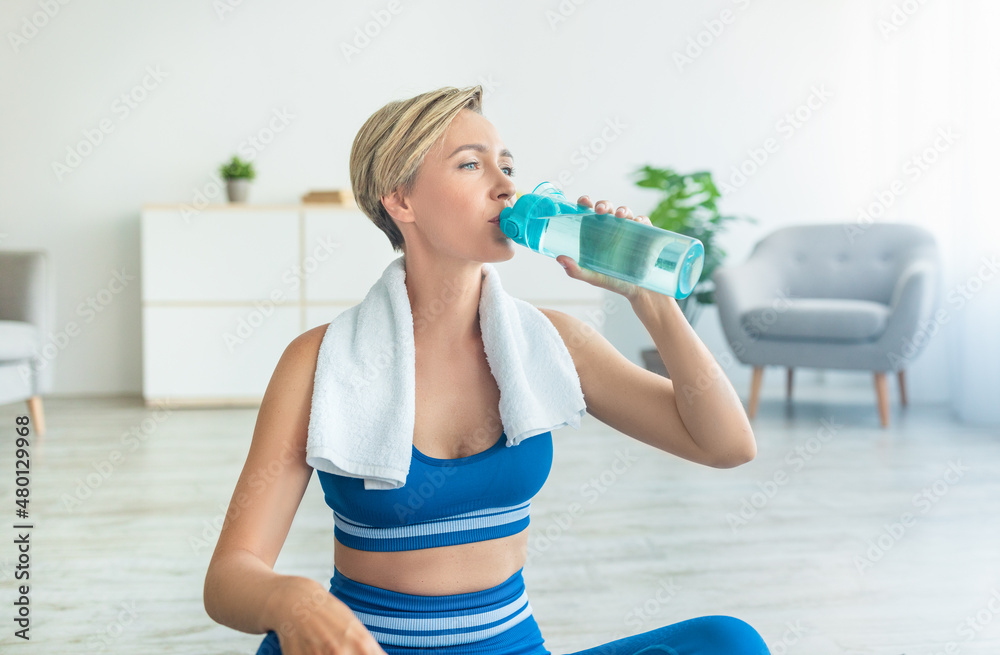 Sporty woman in blue sportswear drinking water Sporty woman in blue sportswear drinking water