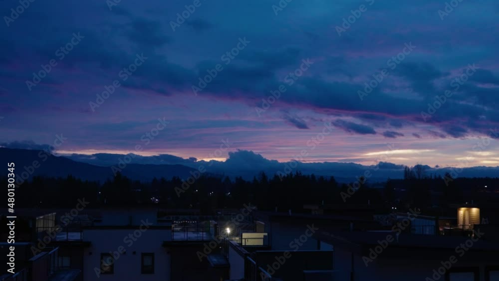 Beautiful purple sunset sky with blue clouds tilting down to reveal townhouses Beautiful purple sunset sky with blue clouds tilting down to reveal townhouses