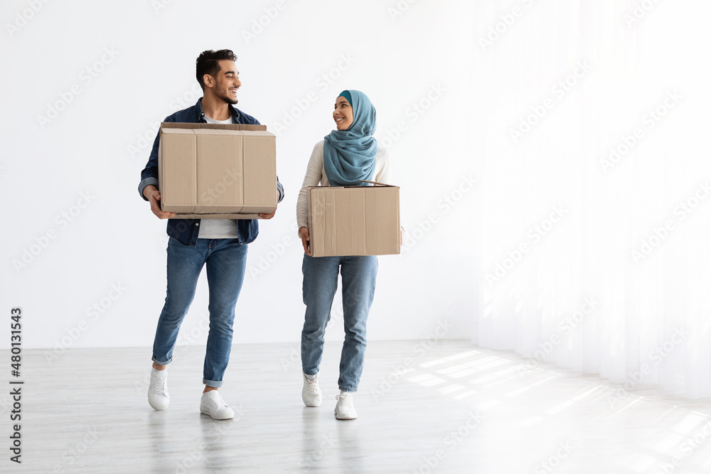 Smiling muslim couple moving to new apartment, full length photo Smiling muslim couple moving to new apartment, full length photo
