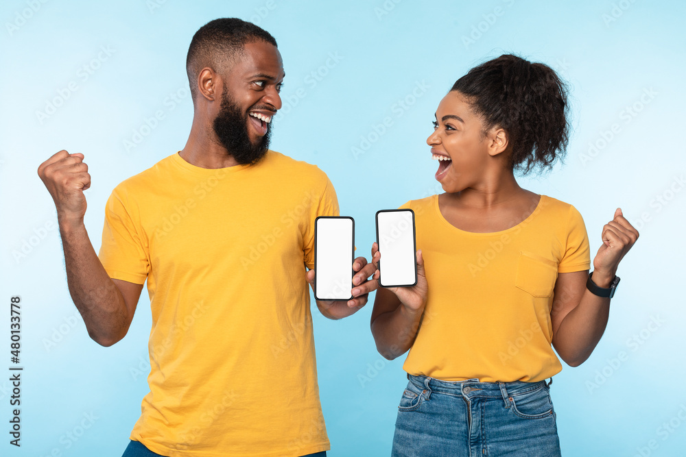 Excited over this new mobile app. Overjoyed black couple holding smartphones with mockup for design, making YES gestures Excited over this new mobile app. Overjoyed black couple holding smartphones with mockup for design, making YES gestures