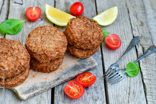 Home made  pork meatballs with  fresh cherry tomatoes on wooden rustic background. Deep fried minced  meat patties on cutting board.
