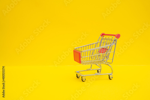 Small steel shopping trolley on yellow surface