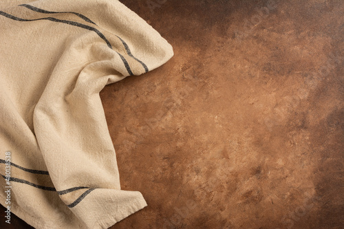 Dramatic light, natural pattern. Cozy soft winter vintage background. Beige Vintage towel on brown background. 
