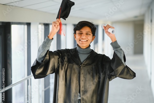 Portrait of indian handsome male graduate in graduation robe and blured background.