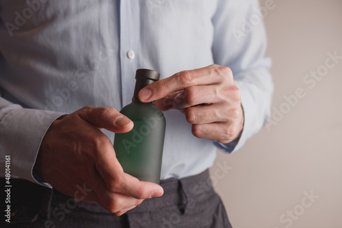 Man in formal wear holding perfume bottle, closeup.  © vladdeep