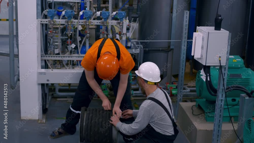 Two employees of the petrochemical industry are working at a formation water treatment plant, twisting the hose of a protective breathing apparatus. Factory work Two employees of the petrochemical industry are working at a formation water treatment plant, twisting the hose of a protective breathing apparatus. Factory work