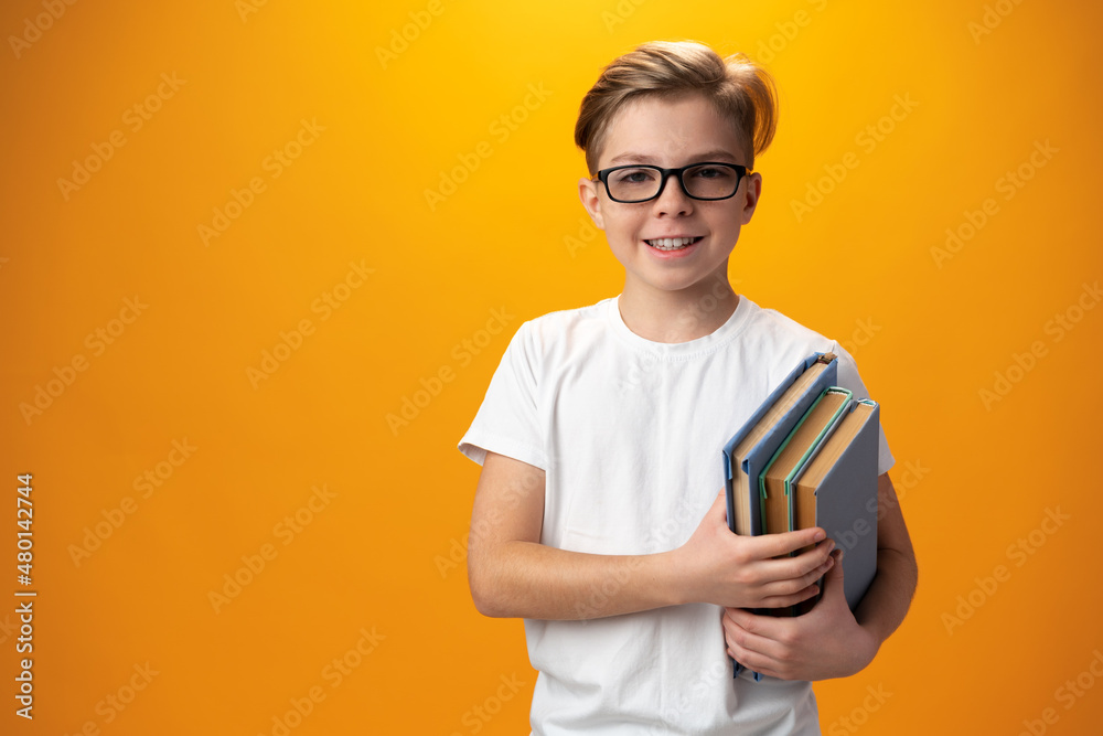 Little schoolboy holding a book against yellow background Little schoolboy holding a book against yellow background