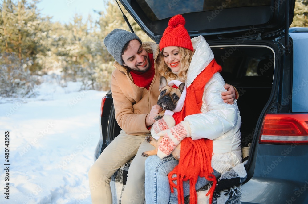 couple guy and girl sitting in car playing with dog in winter forest