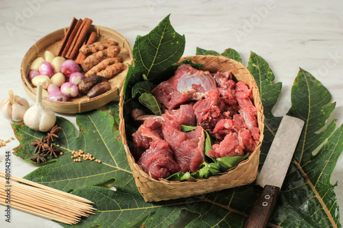 Meat on Bamboo Wooven Box or Besek, with Papaya Leaf Making Beef Tender photo