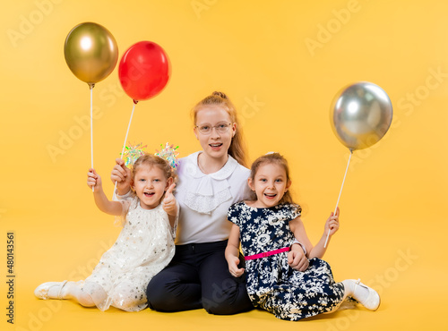 Children with balloons on a yellow background. Birthday, holiday for small