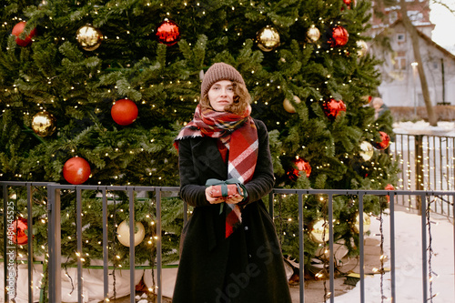 Christmas. Woman in winter clothes with gifts at the Christmas market. Girl outdoors. 