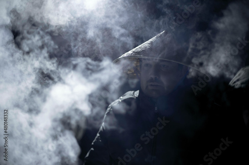 a man in a vietnamese hat in the frost at night around the smoke