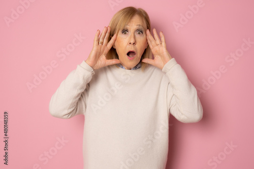 Elderly amazed woman in glasses open mouth gawp look at camera feels stunned isolated on pink background photo