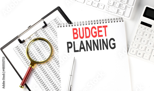 Office desk table with keyboard, notepad ,chart and calculator. Top view with text BUDGET PLANNING