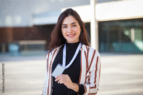 Happy young woman holding an ID card on urban background photo
