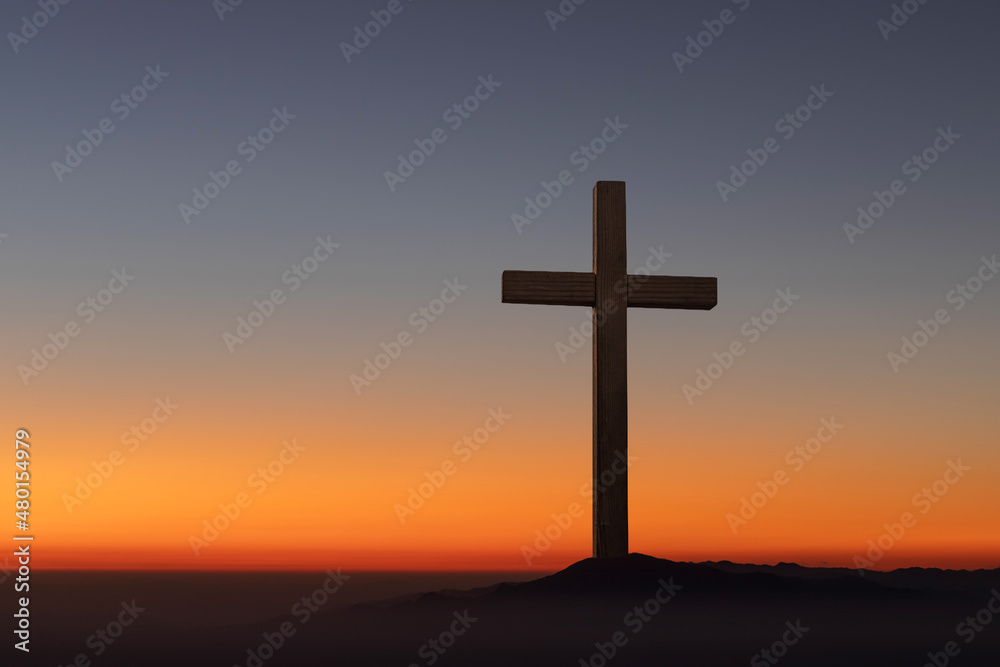Silhouettes of crucifix symbol on top mountain smooth orange blue gradient of dawn sky.