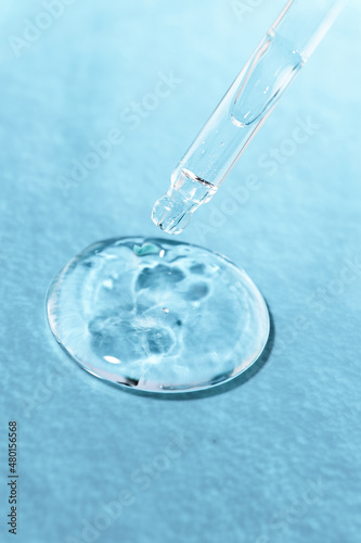 Hyaluronic gel on a blue background with a glass pipette close-up. Cosmetic product for skin moisturizing front view. © Юлия Черкасова