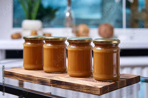 closed jars with homemade caramel on a wooden stand in a row