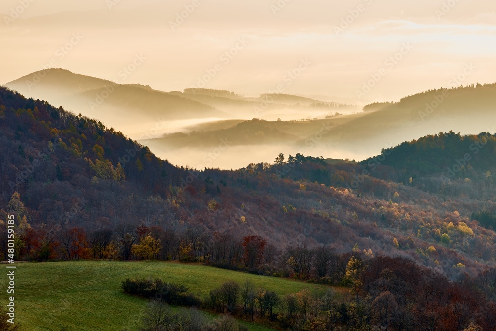 Beautiful mountain landscape with hills in the fog. Morning light at sunrise. Late autumn. Protected area Vrsatec, Slovakia.