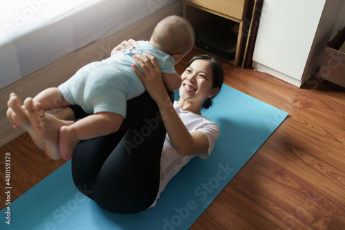 Mom exercising playing with her baby at home, Asian young mother lifting little boy in the air, Yoga, Workout