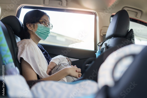 City Life, Asian Mother wearing Protective face mask holding newborn baby boy while sitting in the car