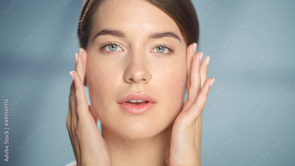 Female Beauty Portrait. Beautiful Caucasian Woman with Brown Hair and Light Green Eyes Posing, Touching Her Natural, Clean Skin. Wellness and Skincare Concept on Soft Isolated Background. Close Up.