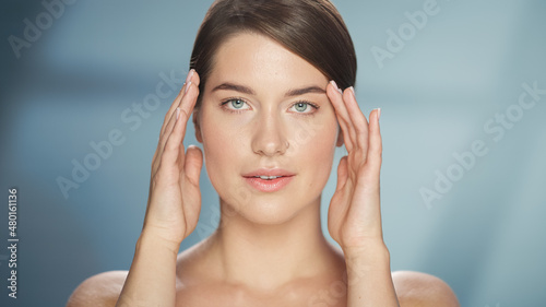 Female Beauty Portrait. Happy Caucasian Woman with Brown Hair and Light Green Eyes Posing, Touching Her Natural, Healthy Skin. Wellness and Skincare Concept on Soft Isolated Background. Close Up.