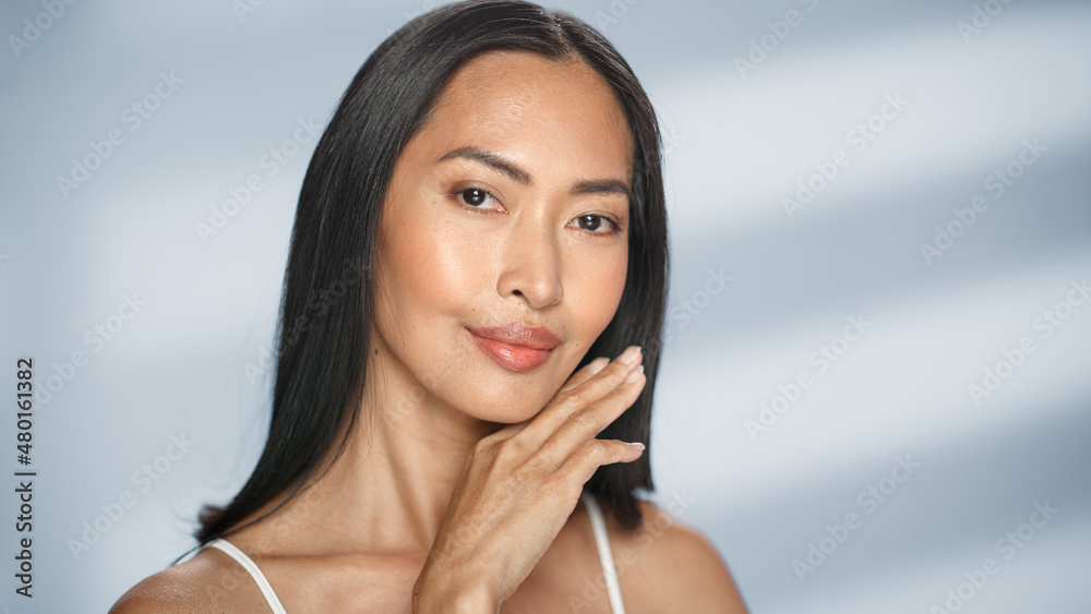 Female Beauty Portrait. Beautiful Asian Brunette Woman Posing, Smiling, Touching Her Face with Natural, Healthy Skin. Wellness and Skincare Concept on Soft Isolated Background. Close Up. Female Beauty Portrait. Beautiful Asian Brunette Woman Posing, Smiling, Touching Her Face with Natural, Healthy Skin. Wellness and Skincare Concept on Soft Isolated Background. Close Up.